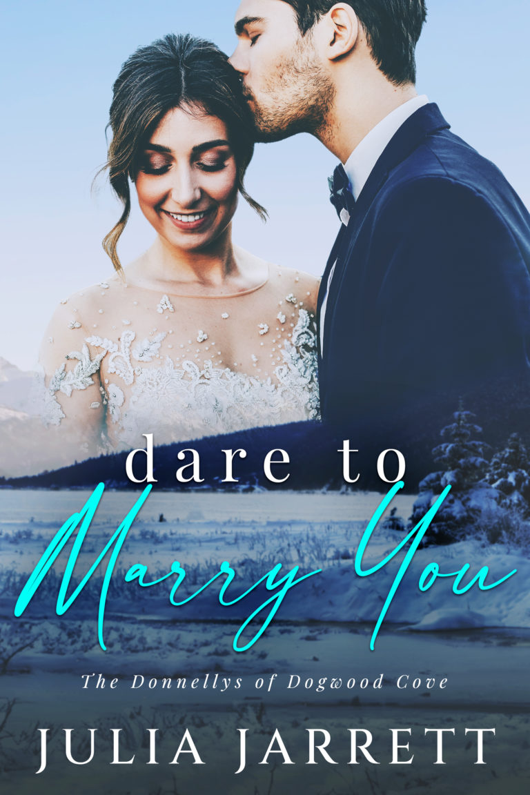 Woman in wedding dress, man in tuxedo. The man is kissing the woman's forehead. Winter mountains landscape with lake at the bottom of the cover. Dare to Marry You (Donnellys at Dogwood Cove Book 5) by Julia Jarrett